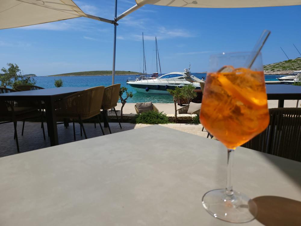 Aperitif an Land, die Yacht in der Bucht