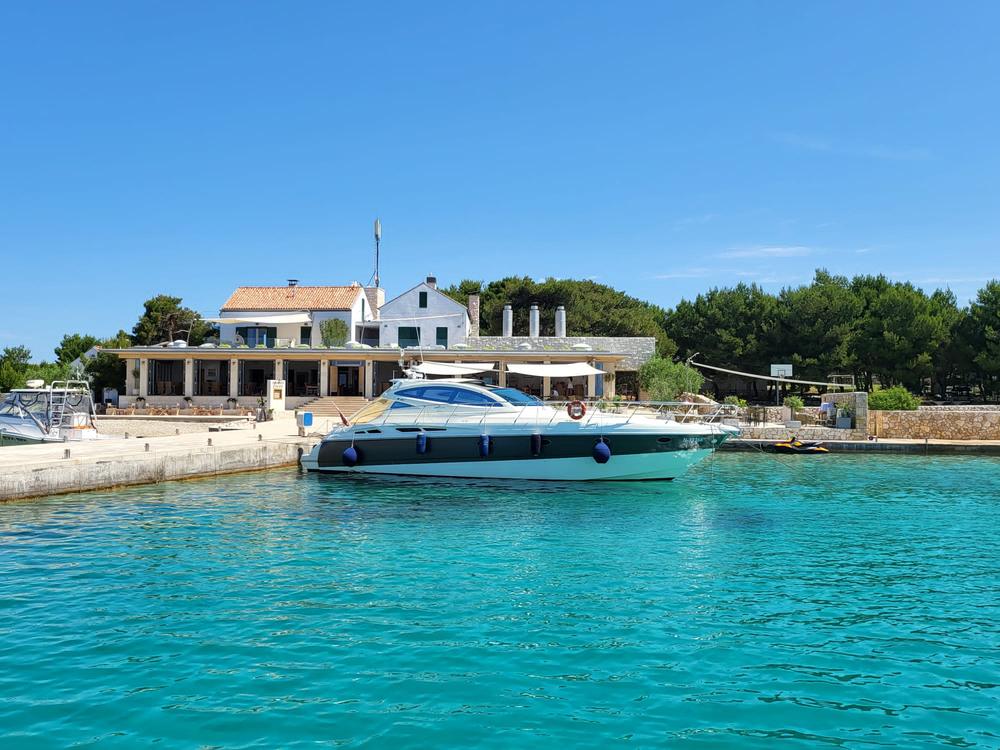 Die Motoryacht Bahia Gloria am Steg einer Konoba, davor das türkisklare Wasser einer Inselbucht
