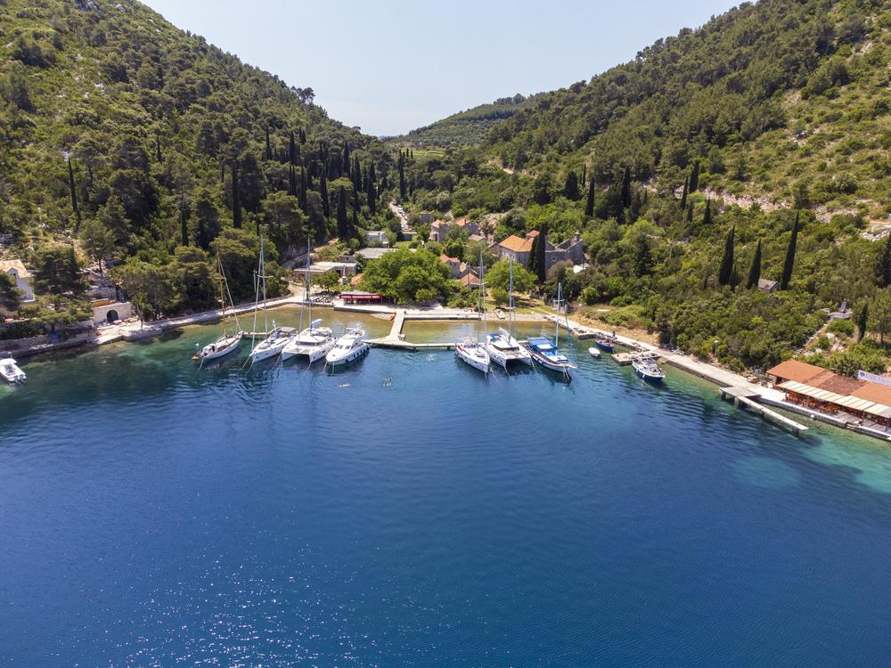 Yachten an einem Steg in einer stillen, grün gesäumten Bucht der Adria