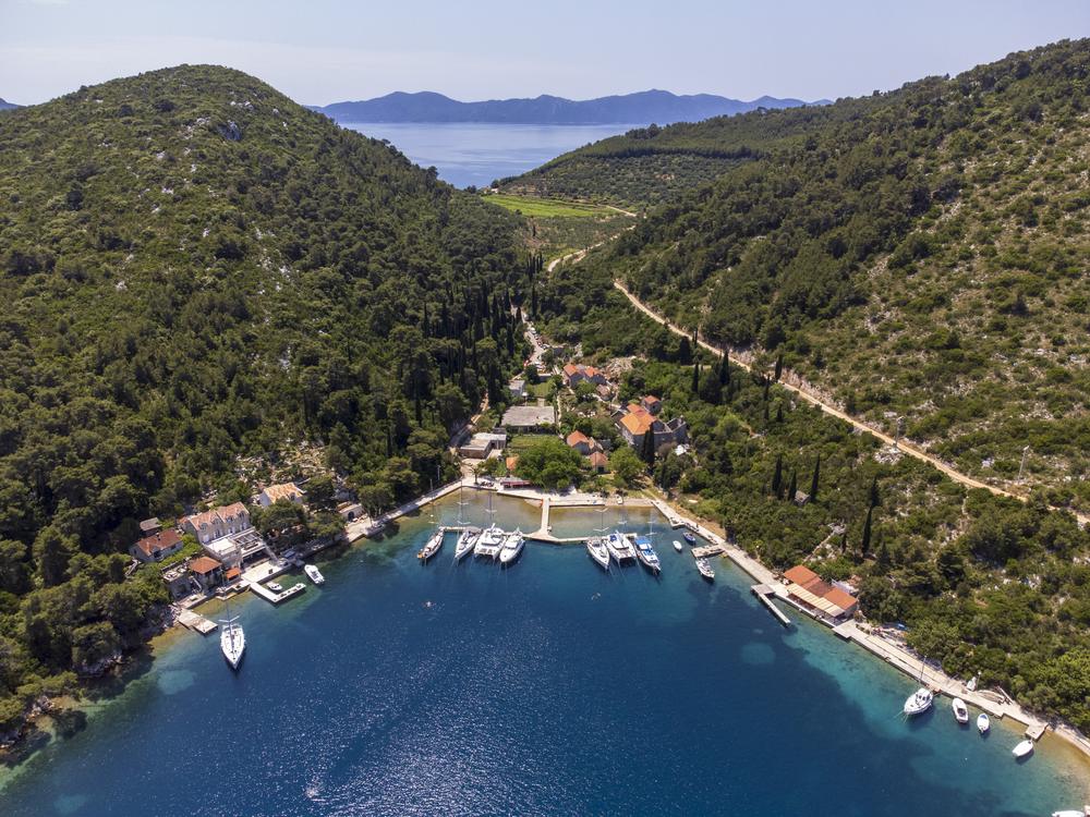 Drohnenaufnahme einer geschützten Bucht an der dalmatinischen Küste, dahinter offenes Meer und Inseln