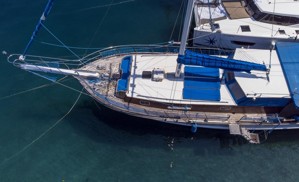 Das Deck der Jambo aus der Drohnenperspektive, daneben klares, türkisgrünes Wasser am Steg der Marina Frapa
